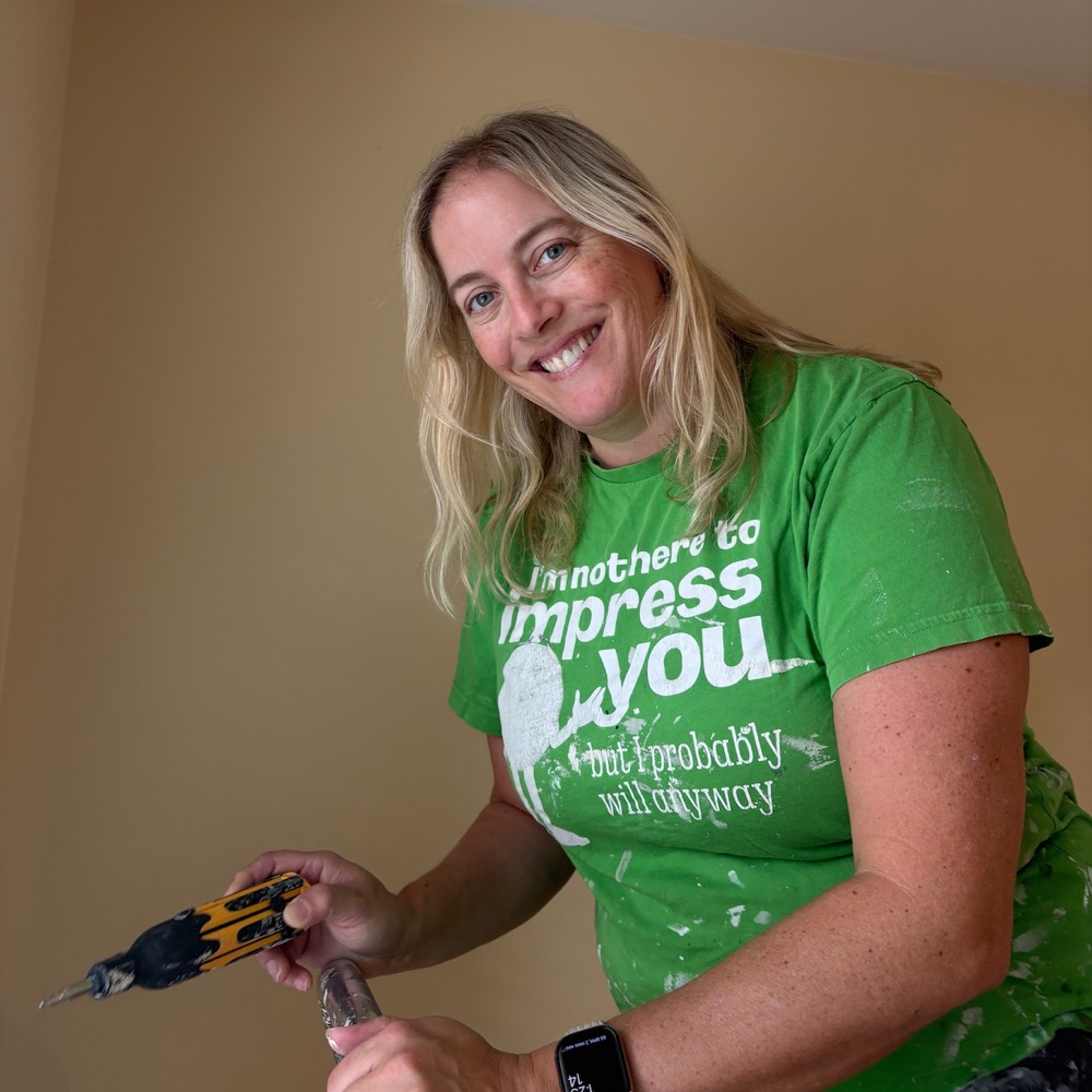 Mackenzie smiling with a drill, mid-job