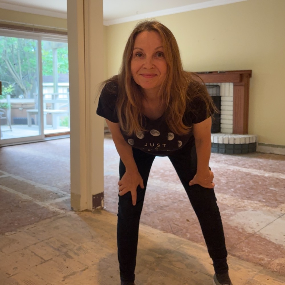 Monika, crouched and grinning in a stripped-out living room