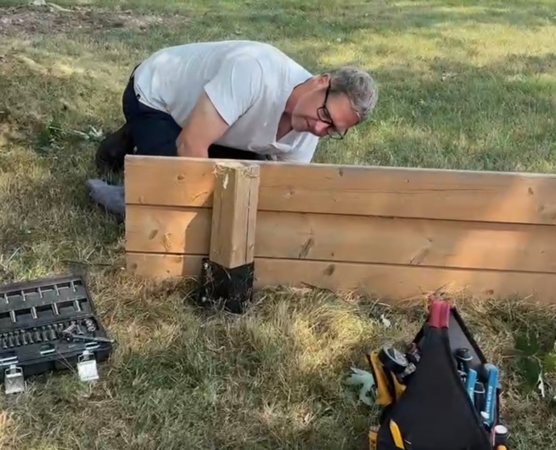 Building a wooden garden box on the lawn, tools spread on the grass