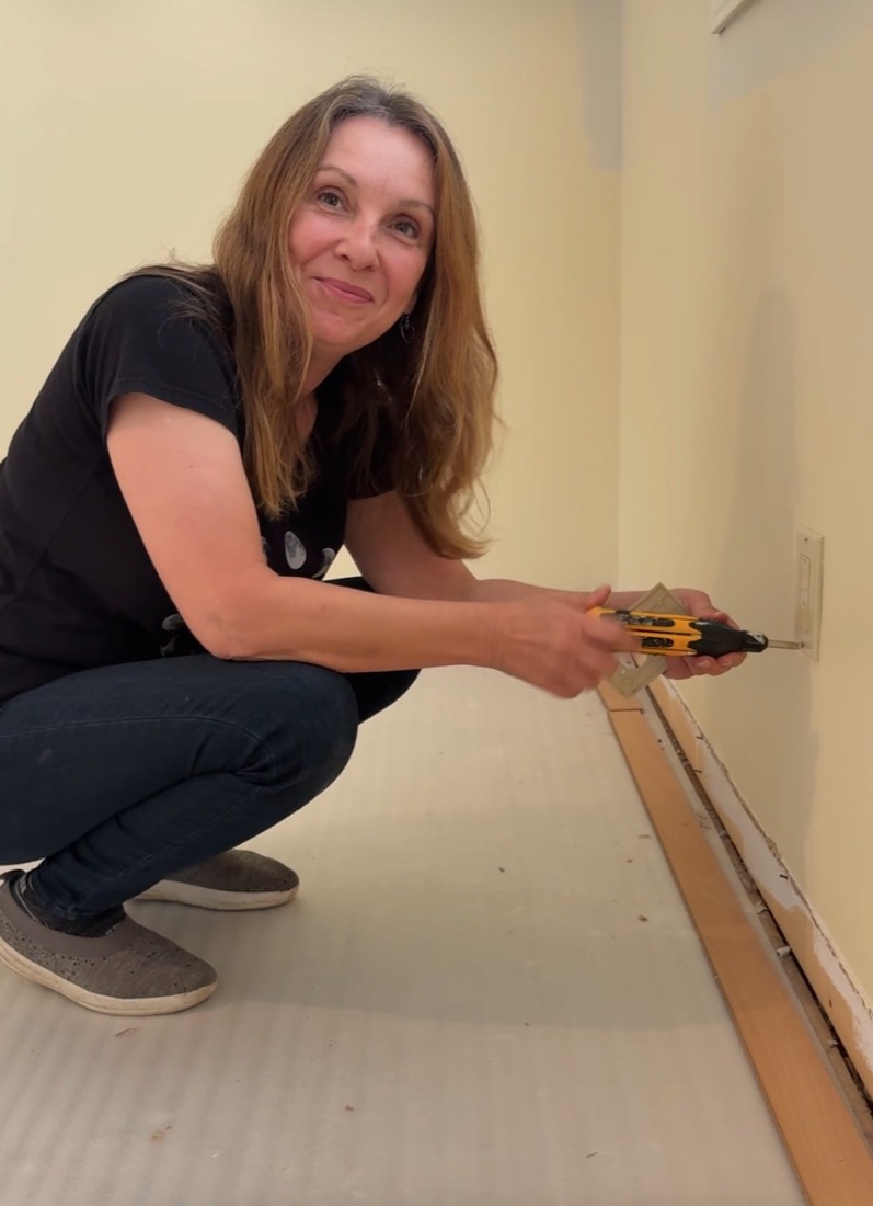 Crouched with a drill, mid-job, smiling